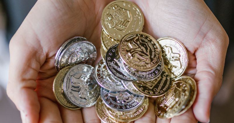 hand holding out variety of gold and silver coins